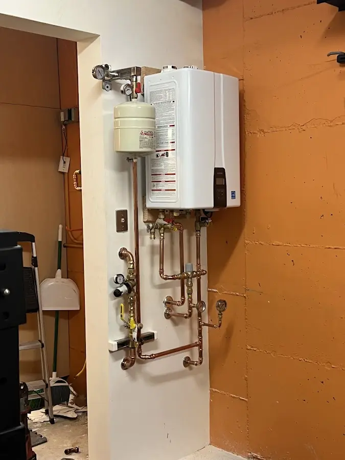 Plumbing technician inspecting water heater connections in Fairhaven